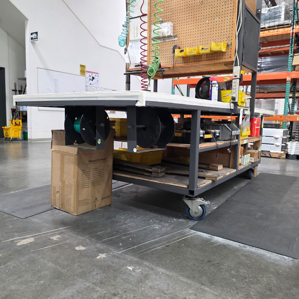 STEEL ASSEMBLY TABLE ON CASTERS, W/ 11' X 4' WOOD TOP, 37" TOP HT, W/ CENTER STORAGE & LIGHTS, CONTENTS NOT INCLUDED-174