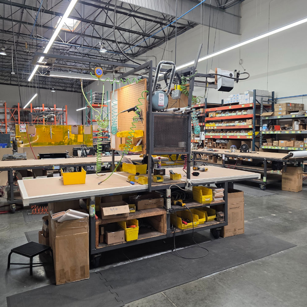 STEEL ASSEMBLY TABLE ON CASTERS, W/ 11' X 4' WOOD TOP, 37" TOP HT, W/ CENTER STORAGE & LIGHTS, CONTENTS NOT INCLUDED-174