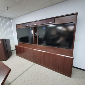 LOT - CONFERENCE ROOM GROUPING: CONFERENCE TABLE W/ FLIP-PANELS FOR MONITORS, AUDIO VIDEO CABINET W/ (2) 65" LCD SCREENS AND DIGITAL TIME ZONE CLOCK, FREESTANDING PODIUM, COLOR: MAHOGANY-189