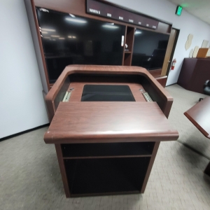 LOT - CONFERENCE ROOM GROUPING: CONFERENCE TABLE W/ FLIP-PANELS FOR MONITORS, AUDIO VIDEO CABINET W/ (2) 65" LCD SCREENS AND DIGITAL TIME ZONE CLOCK, FREESTANDING PODIUM, COLOR: MAHOGANY-189