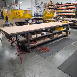 STEEL TABLE ON CASTERS W/ 14' X 4' PLYWOOD TOP, 37" TOP HT, CONTENTS NOT INCLUDED-173