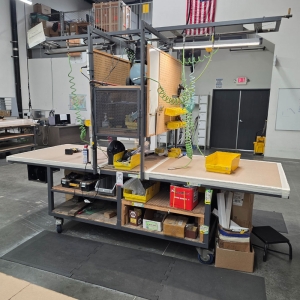 STEEL ASSEMBLY TABLE ON CASTERS, W/ 11' X 4' WOOD TOP, 37" TOP HT, W/ CENTER STORAGE & LIGHTS, CONTENTS NOT INCLUDED-174