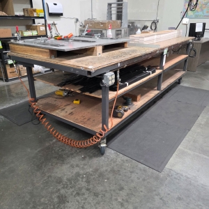 STEEL TABLE ON CASTERS W/ 11' X 4' PLYWOOD TOP, 37" TOP HT, CONTENTS NOT INCLUDED-181